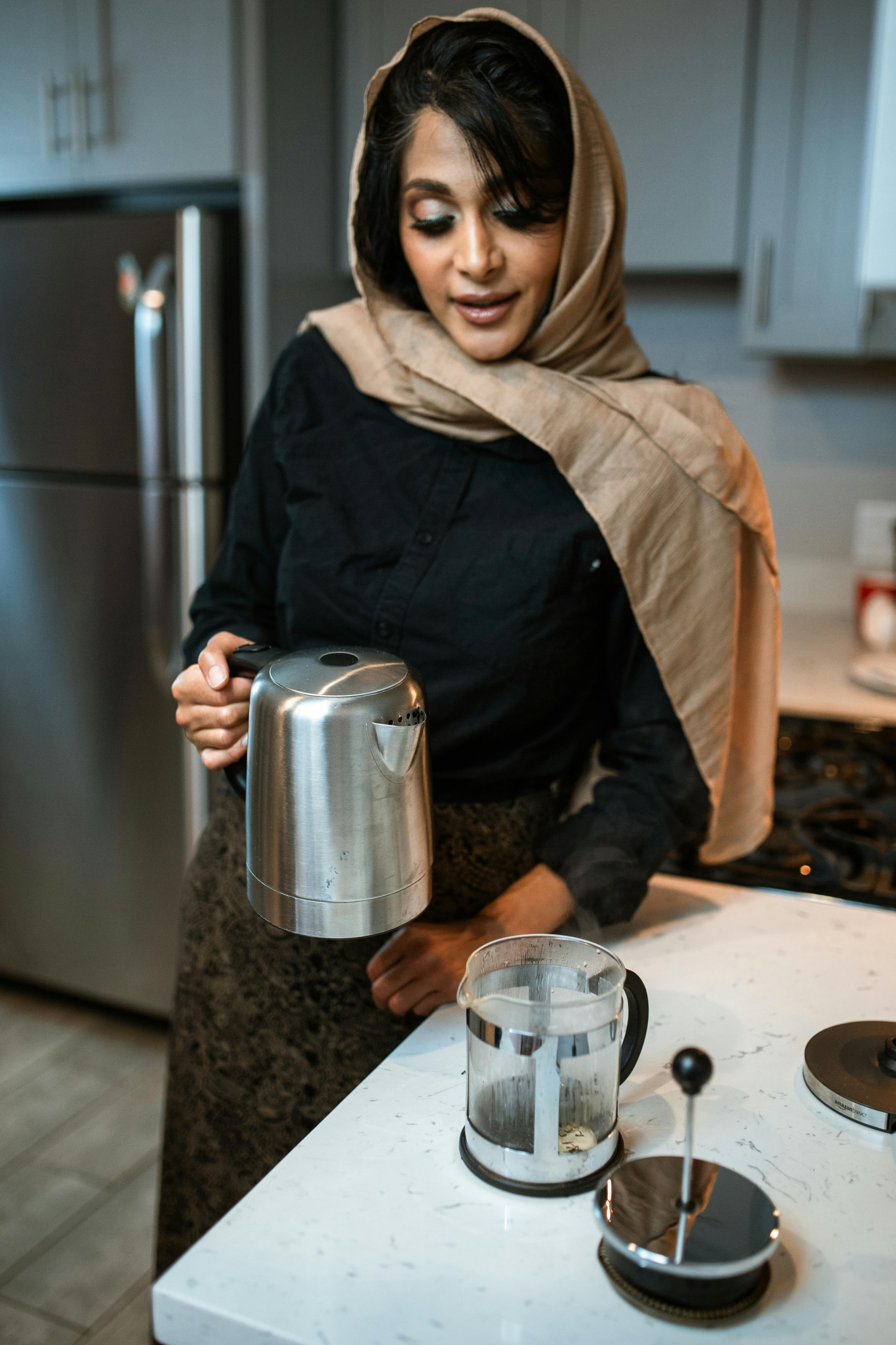一名穆斯林妇女在现代厨房里将热水倒进法压壶