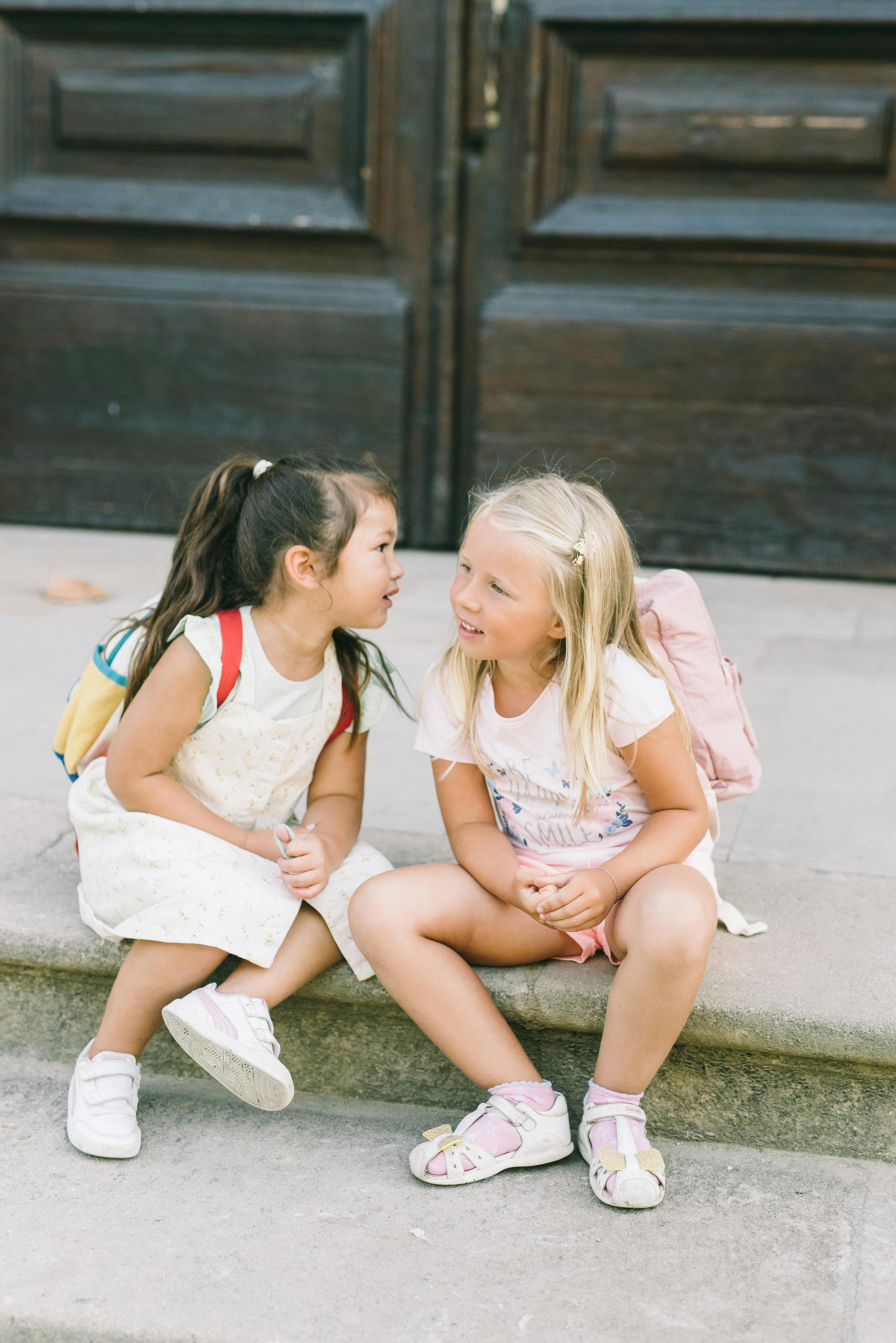 两个年轻女孩坐在户外的石阶上，分享着快乐的时光