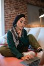 一位专注于传统服装的女性在家中使用笔记本电脑远程工作