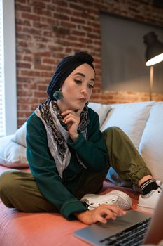 一位专注于传统服装的女性在家中使用笔记本电脑远程工作