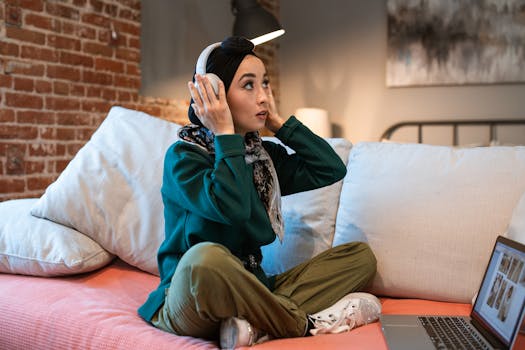 Focused young woman listening to music on headphones while working from home on her laptop.