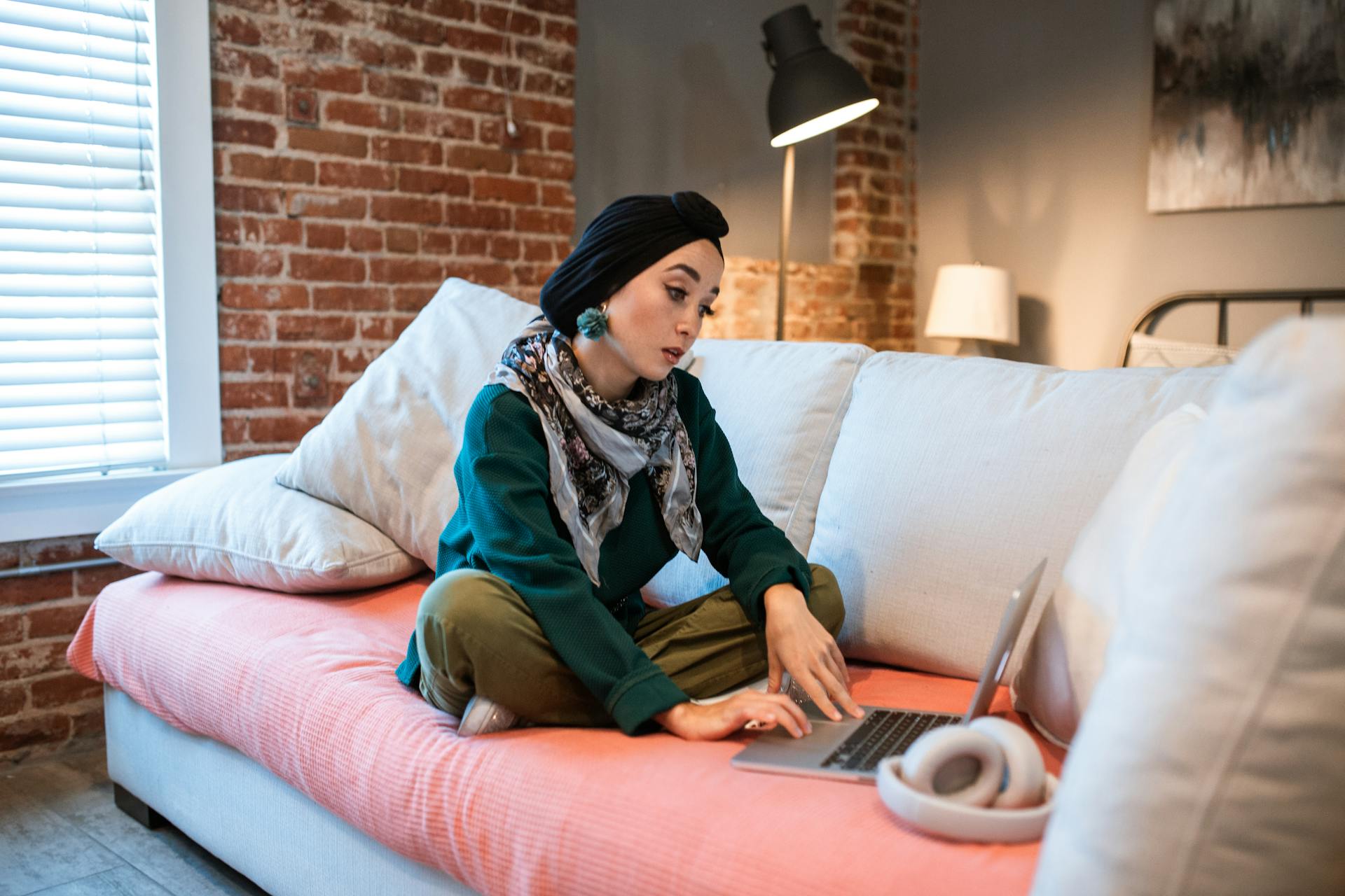 Woman sitting on a couch with a laptop, illustrating a remote work lifestyle indoors.