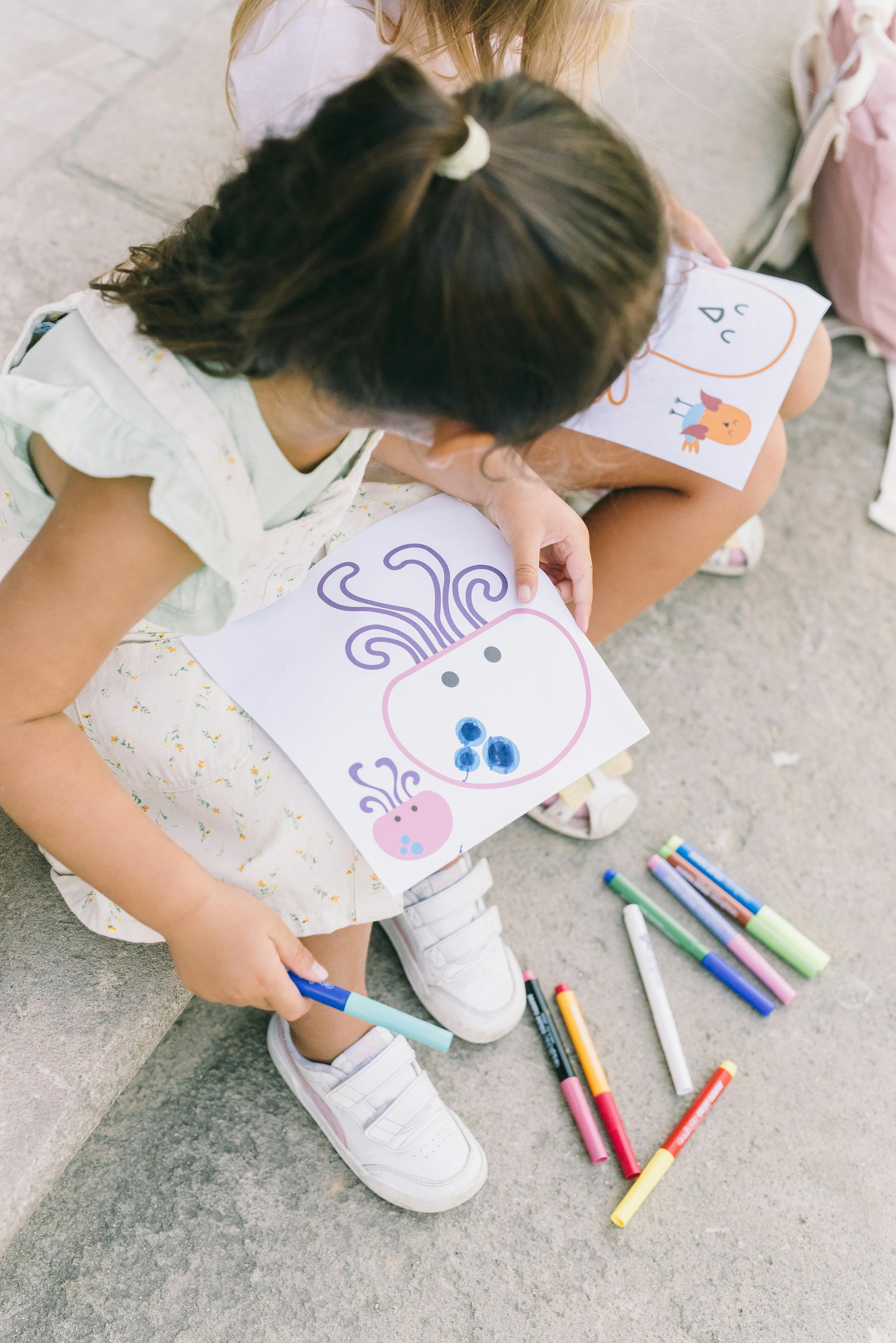 little girls holding drawings