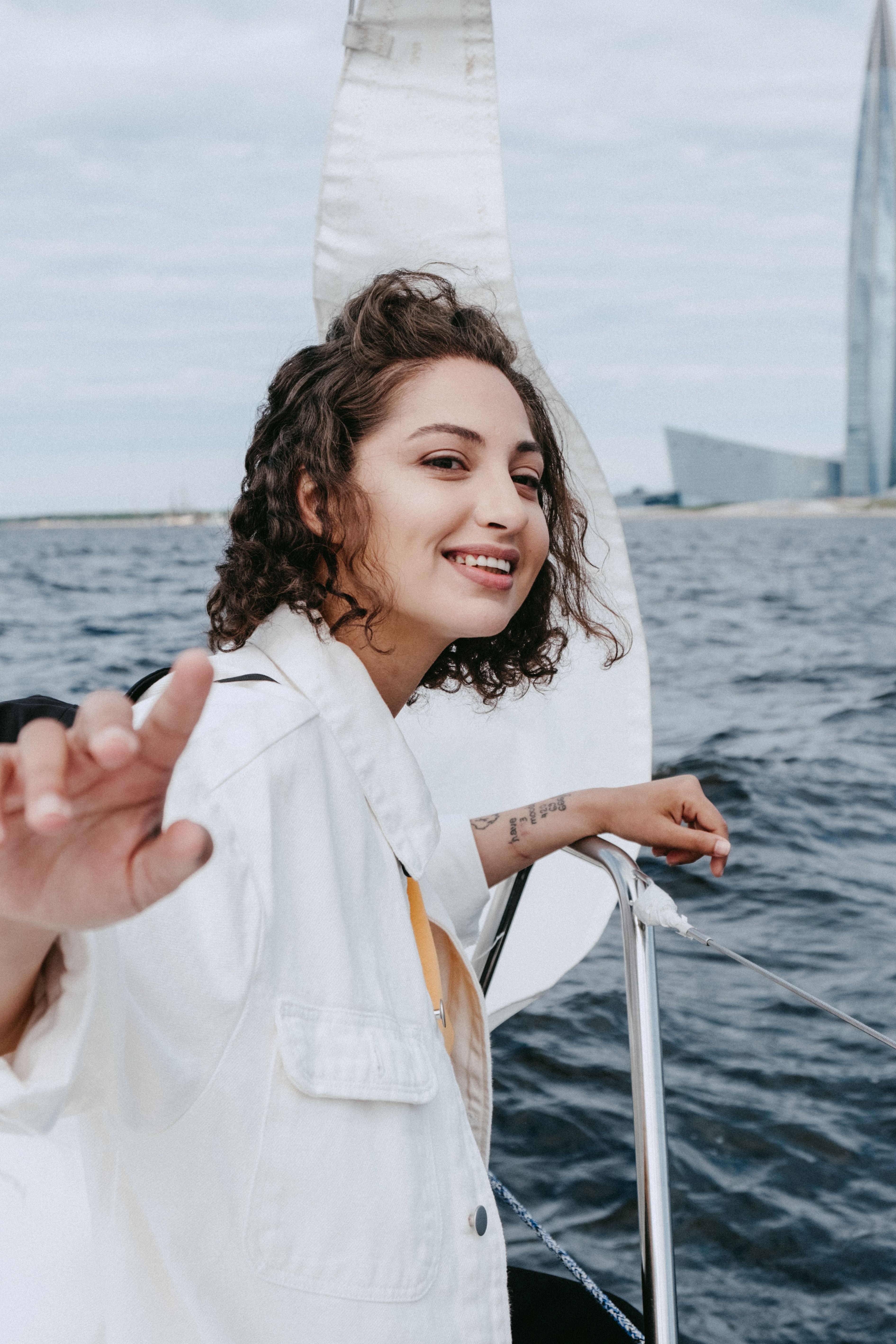 一个女人微笑着享受游艇之旅，背景是大海和城市景观