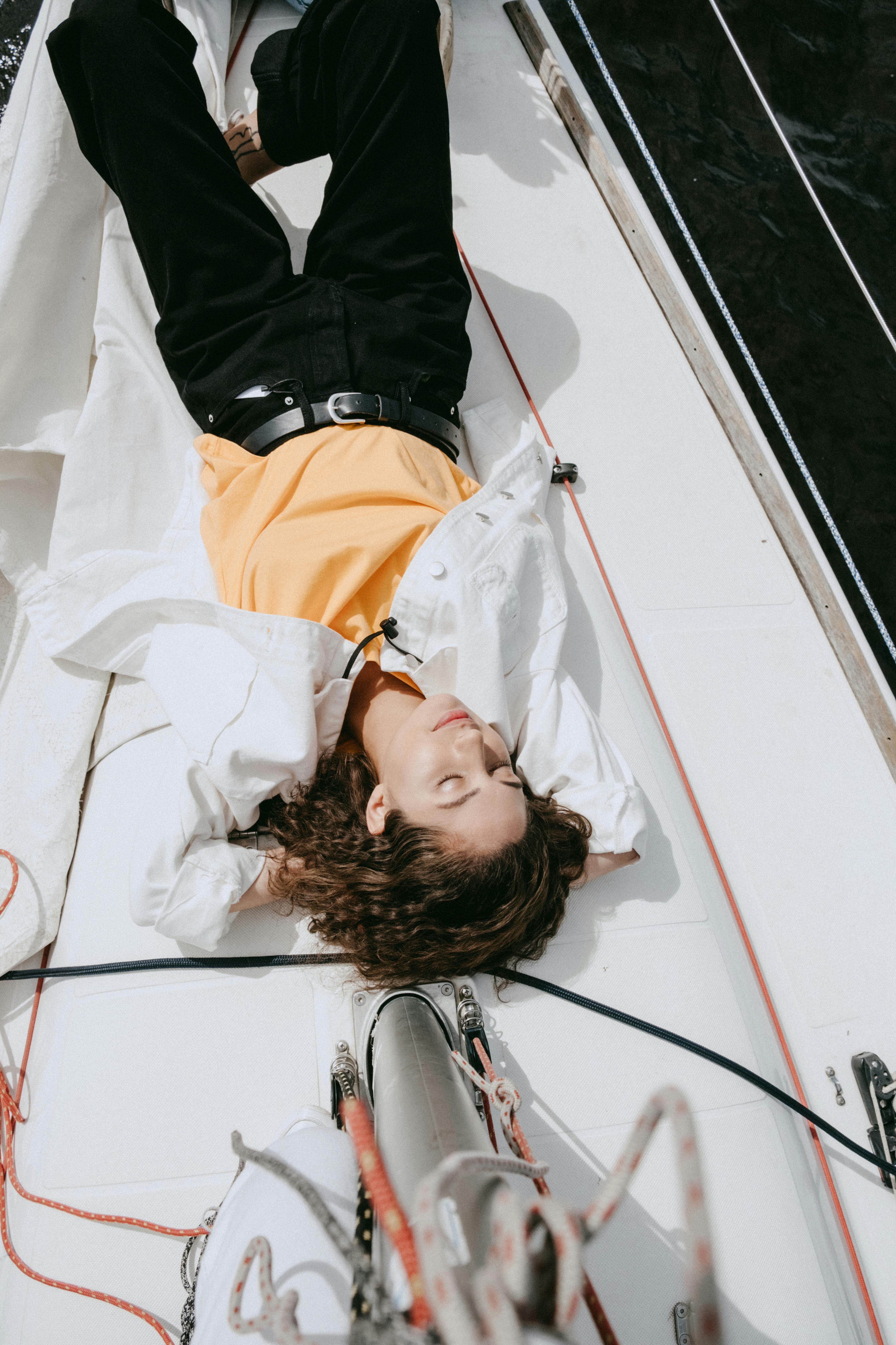 woman in black jacket lying on white bed