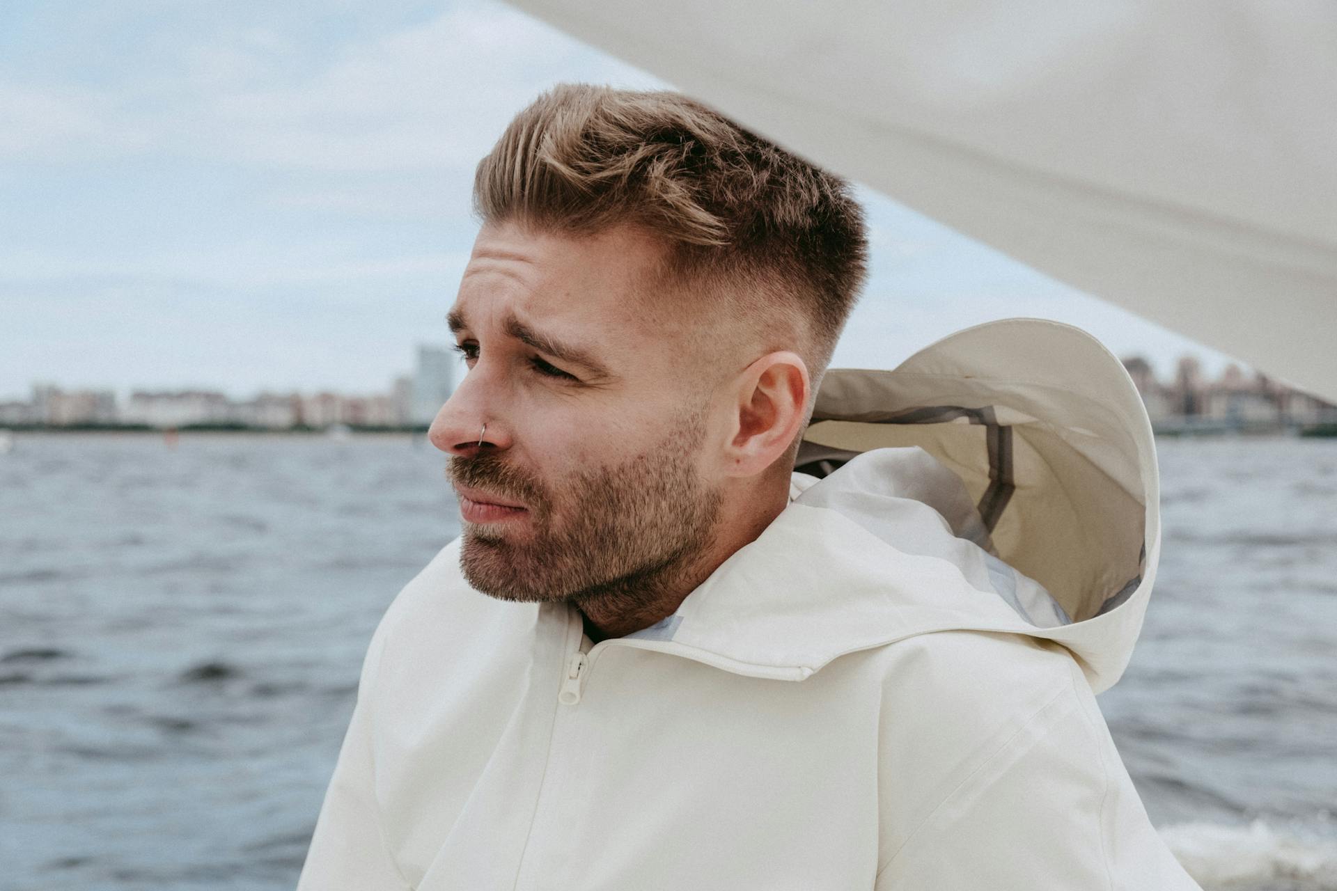 A young man enjoying a sailing adventure on a yacht against a scenic water backdrop.