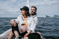 Man in White Dress Shirt and Woman in White Dress Shirt Sitting on Boat