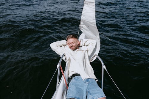 Free Woman in White Hoodie and Blue Denim Shorts Sitting on White Boat Stock Photo