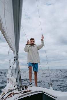 An adult man skillfully navigating a yacht on a calm summer day out in the open sea.