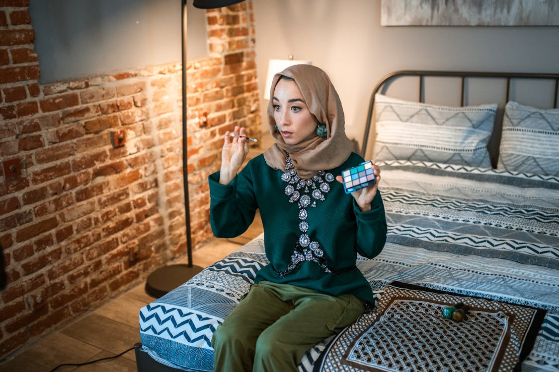 Woman Sitting on Bed Showing an Eyeshadow Palette