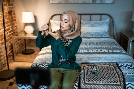 A stylish woman vlogger applies makeup in a cozy bedroom setting, showcasing beauty products and elegant clothing.