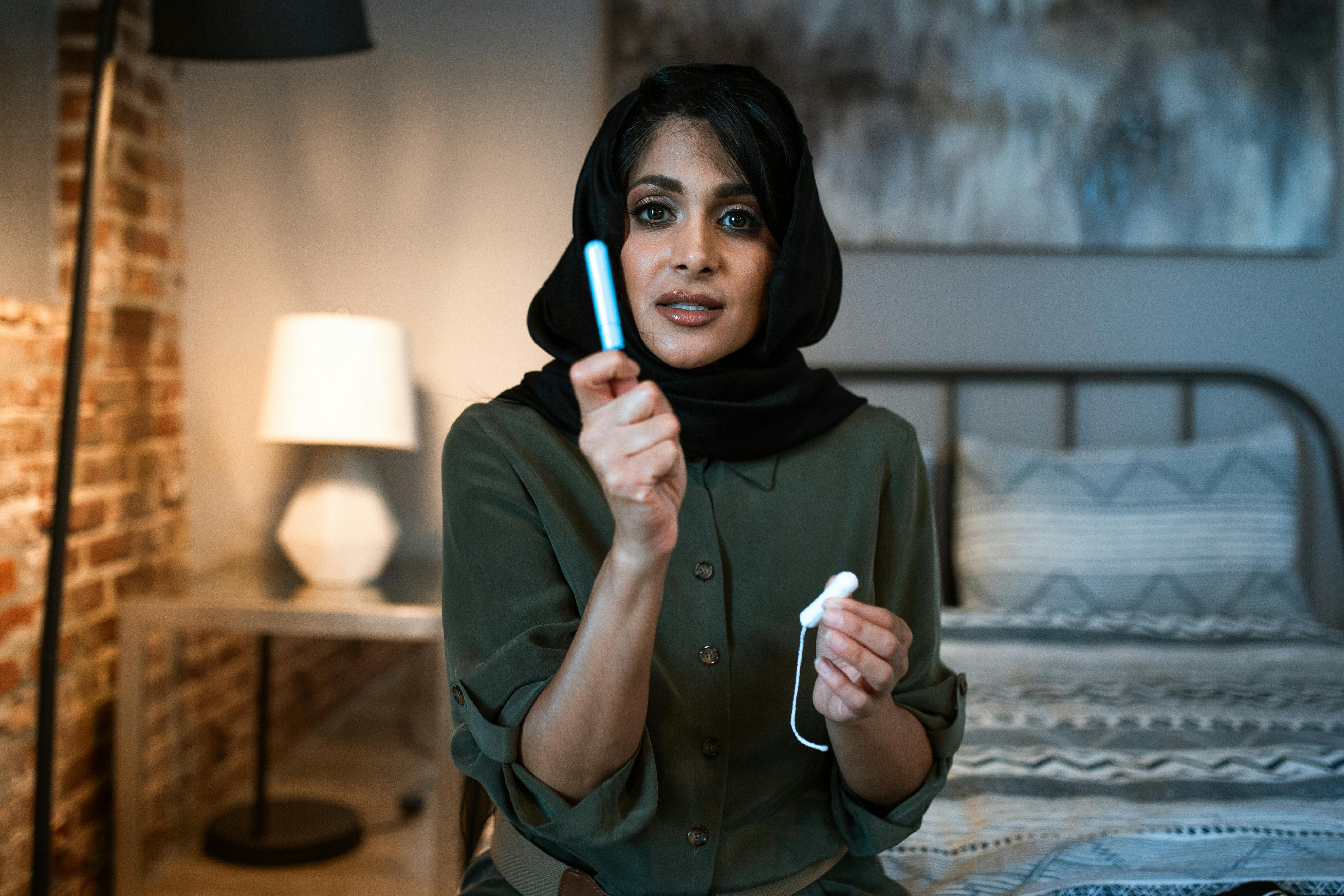 woman in a hijab holding a tampon