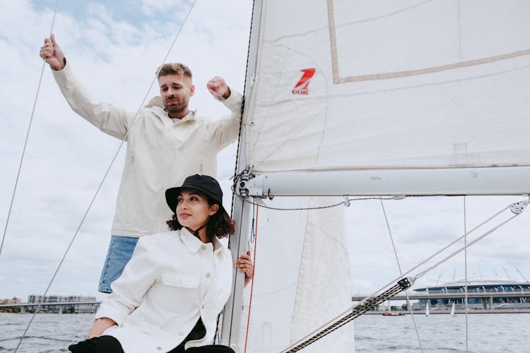 Man In White Dress Shirt And Black Cap Standing Beside Woman In White Long Sleeve Shirt