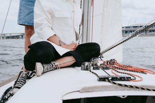 Man in White Button Up Shirt Sitting on White Boat