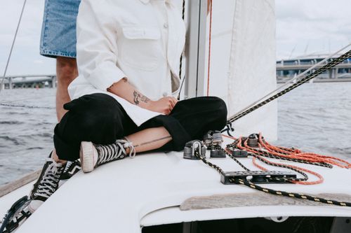 Free Two people enjoying a leisure sailing trip on a yacht with clear summer skies. Stock Photo