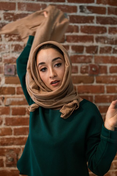 Free Confident woman in hijab posing indoors against a brick wall, showcasing modern fashion. Stock Photo