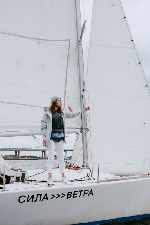 Woman in Blue Denim Jacket and White Pants Standing on White Boat