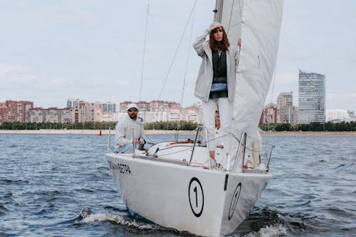 Man in White Long Sleeve Shirt and Pants Standing on White Boat