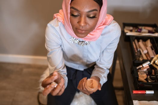 Elegant woman in hijab applying makeup with traditional wear, epitomizing beauty and style.
