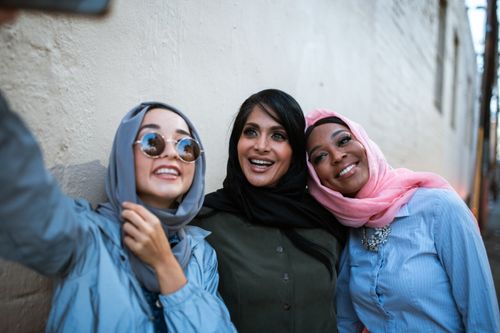 Free Three smiling women in colorful hijabs take a selfie outdoors, showcasing diversity and friendship. Stock Photo