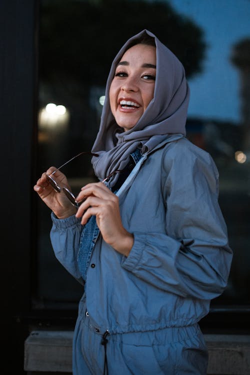Женщина в синей толстовке с капюшоном, держащей смартфон