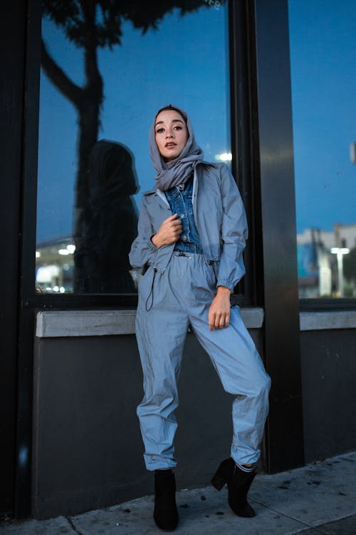 A Young Woman Wearing Gray Hijab Standing Beside a Glass Wall