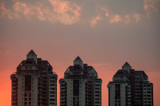 Silhouetted high-rise buildings against a vibrant sunset sky with scattered clouds.