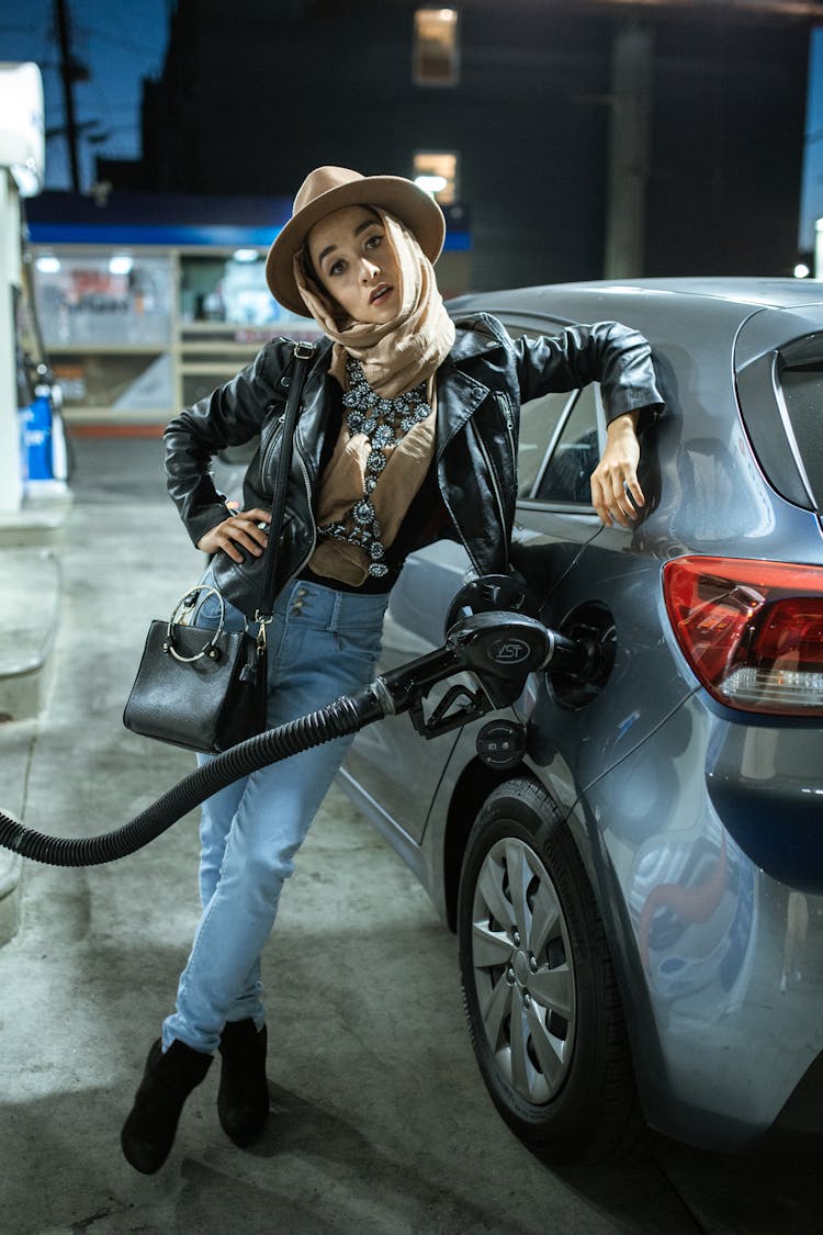 A Yong Woman With Headscarf Filling Up The Tank With Gas