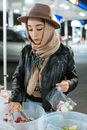 一位年轻女子头戴时尚头巾，在户外市场挑选新鲜农产品