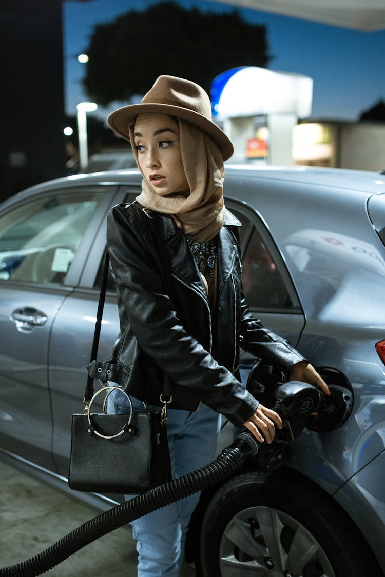 A Woman Holding The Gas Pump To The Gas Tank