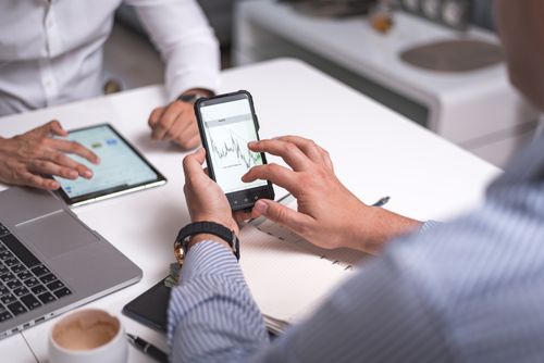 Free Business professionals collaborating with smartphones and tablets analyzing digital charts. Stock Photo