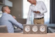 Two businessmen in an office with clocks displaying Dubai, Sofia, London time.