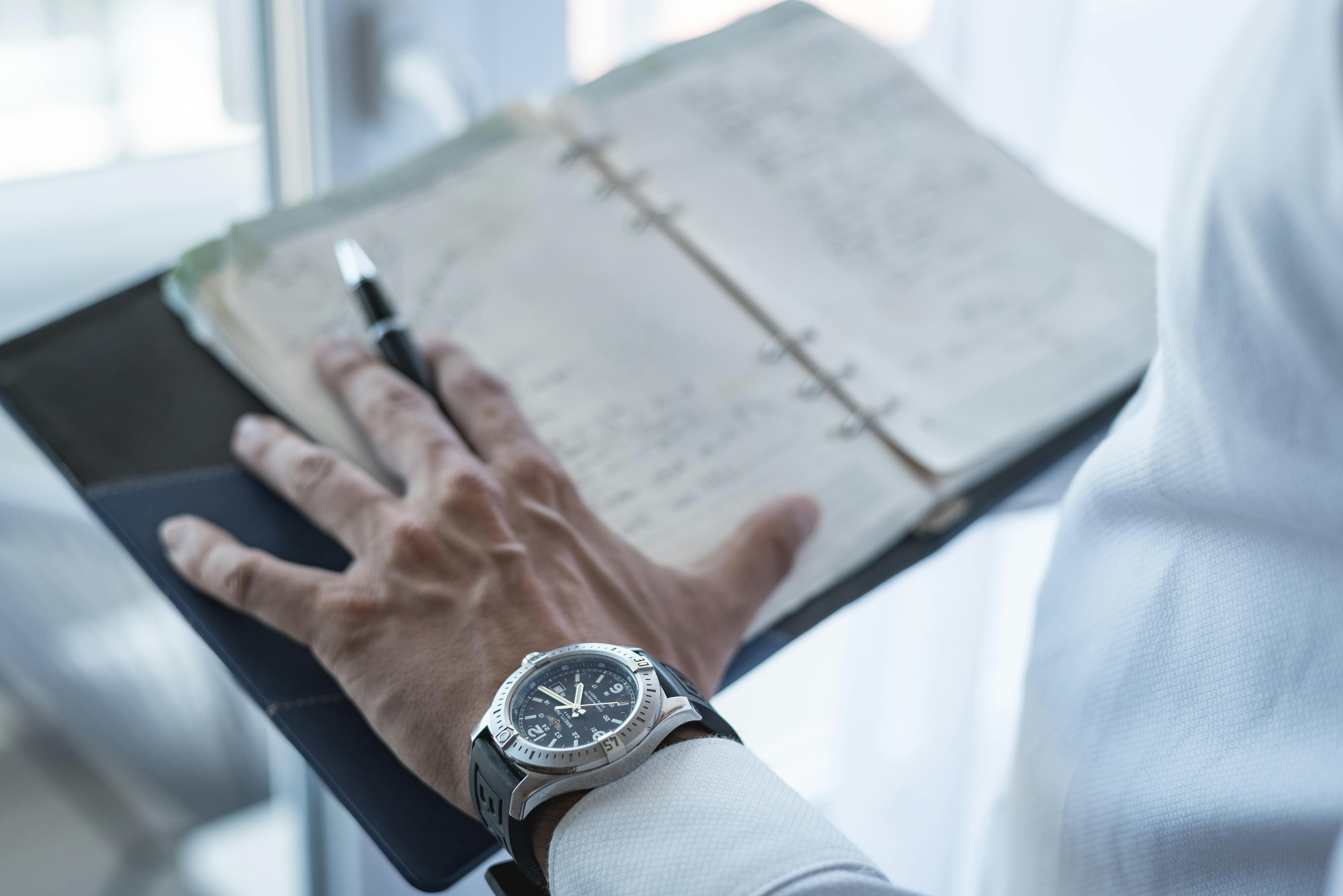 Elegant close-up of a hand writing in a notebook, featuring a classy wristwatch, in Sofia, Bulgaria.