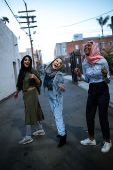 三位年轻女性穿着时尚服装，在城市街道上分享欢笑与欢乐