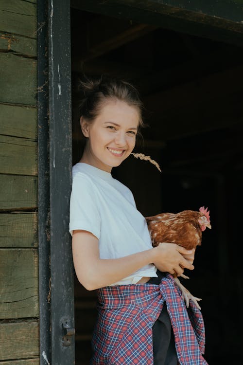 Free Girl in Blue Crew Neck T-shirt Holding Brown Hen Stock Photo