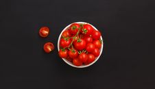 Bowl with ripe cherry tomatoes on black background