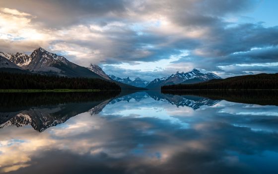 Peaceful water of clean lake reflecting mountain ridge and cloudy sunset sky in evening in nature