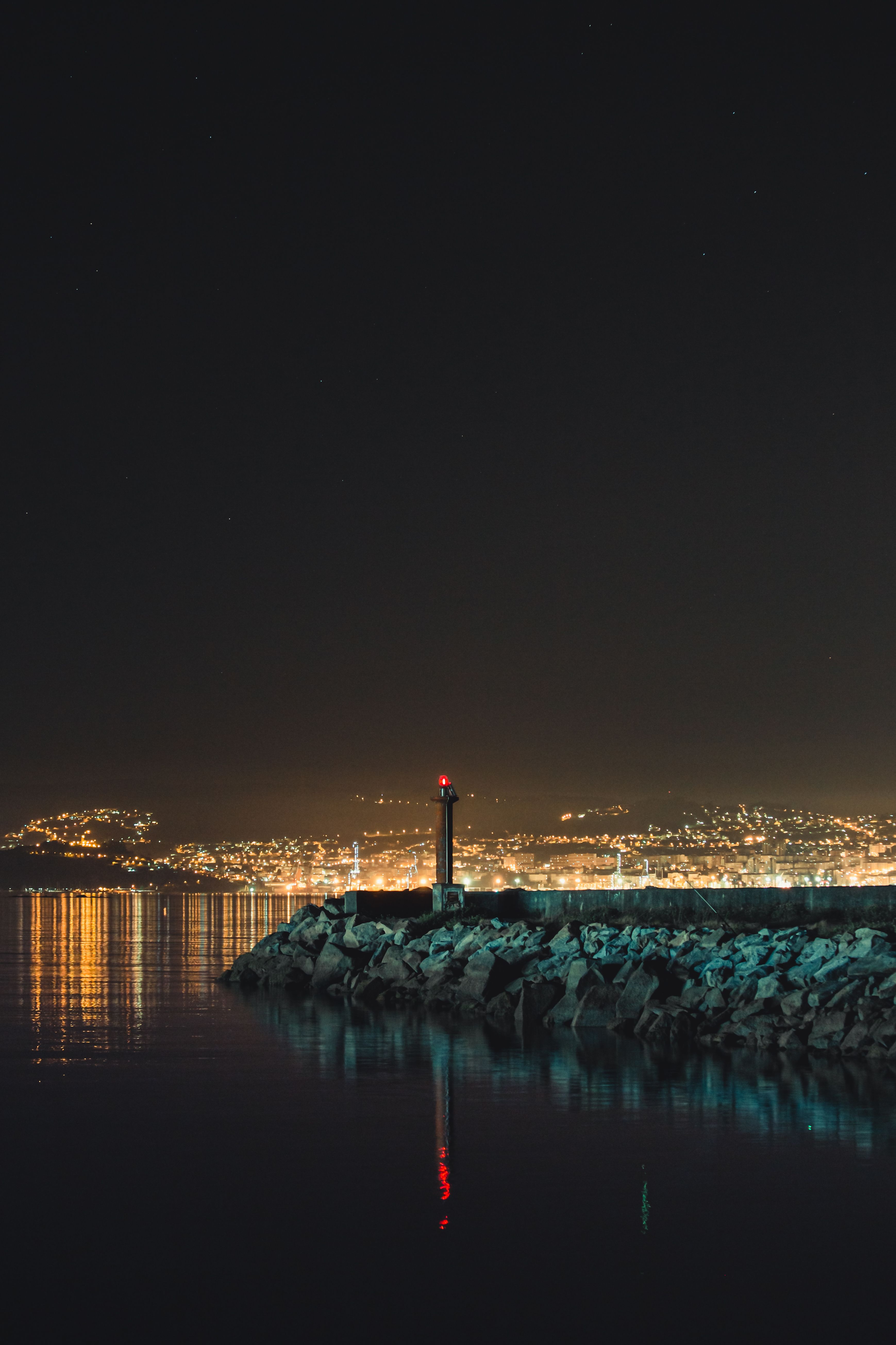 矗立在崎岖海岸上的灯塔风景如画，夜晚灯光在天空下闪烁