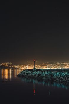 矗立在崎岖海岸上的灯塔风景如画，夜晚灯光在天空下闪烁