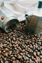 From above of shiny metallic coffee pot near roasted beans with pleasant aroma and textile bag