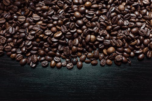 Top view of bright crispy halves of coffee beans with pleasant smell on black surface