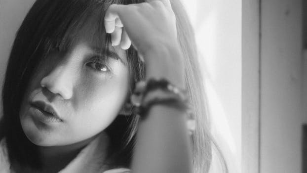 Black and white portrait of a woman looking contemplatively at the camera, indoors.