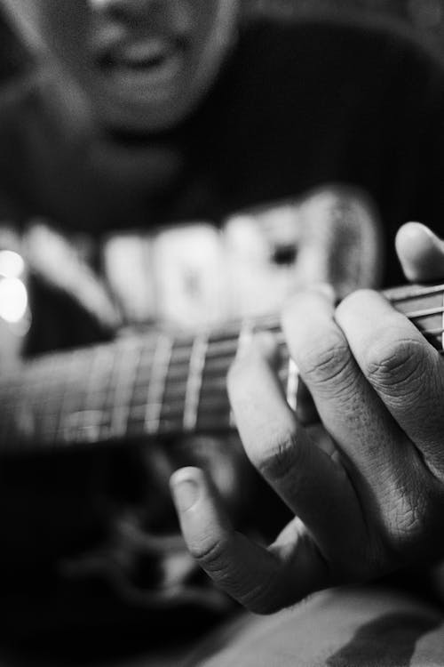 Crop person playing guitar during rehearsal