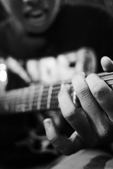 Black and white unrecognizable person touching strings on guitar neck while playing song during rehearsal