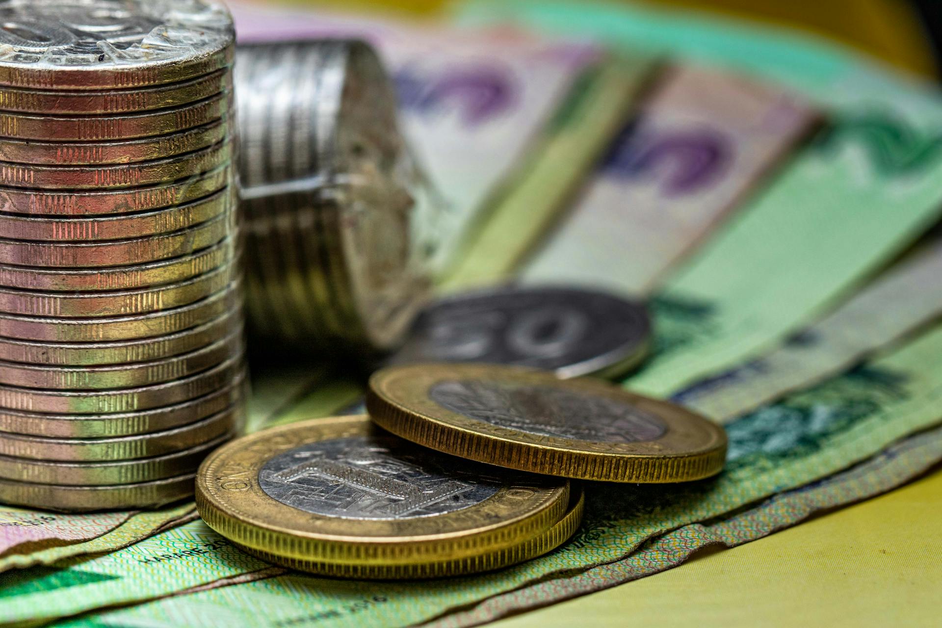 Close-up image of stacked coins and various currency notes, representing financial concepts.