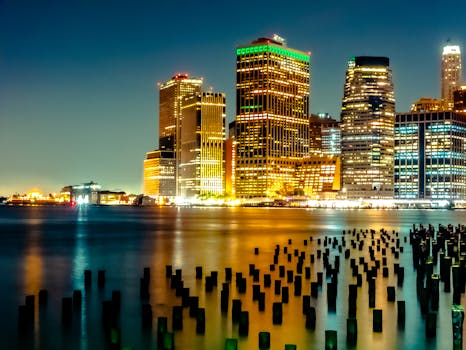 Captivating view of New York City skyline at night with illuminated skyscrapers and reflections.
