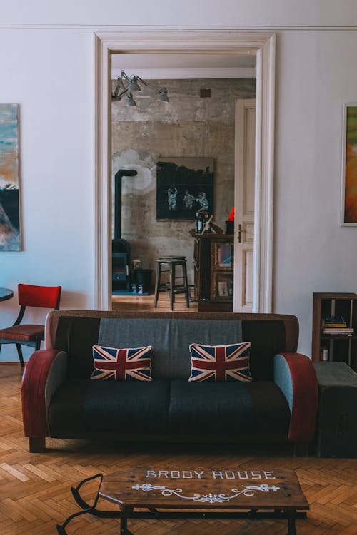 Free Interior of stylish living room with comfortable couch decorated with United Kingdom flag cushions and wooden furniture and floor Stock Photo