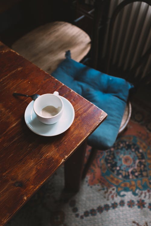 クラシックなスタイルのアパートのぼろぼろの木製テーブルに置かれたカプチーノのカップ