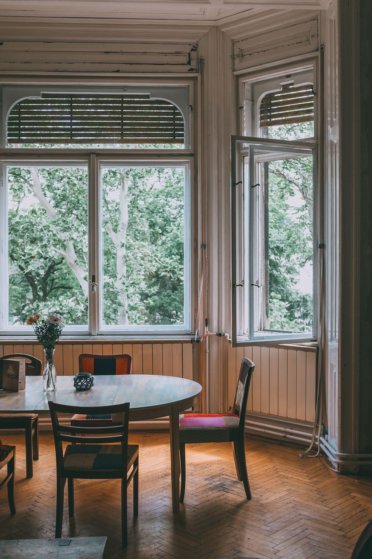 Oval wooden table with chairs near bright windows