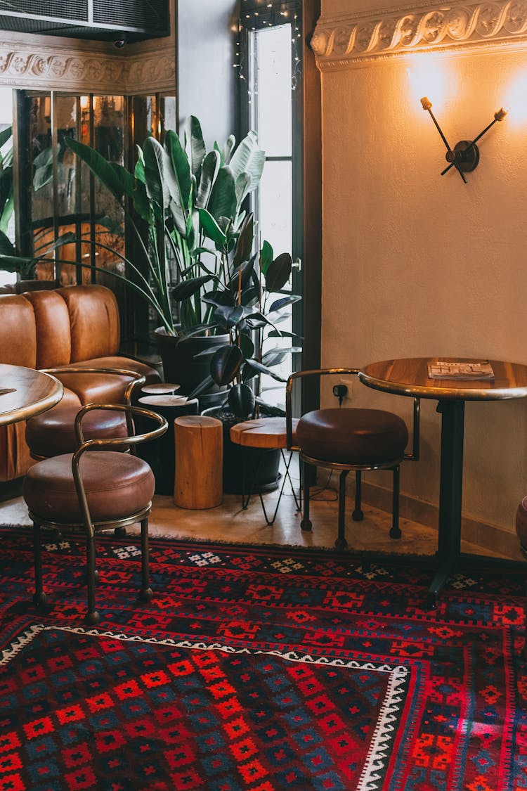 Interior Of Stylish Cafe With Wooden Tables And Leather Chairs Decorated With Antique Carpet